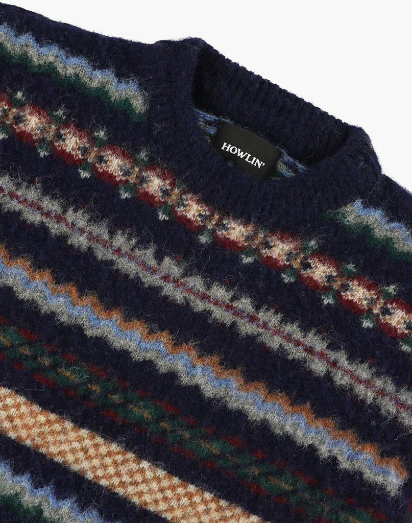 Howlin' Woolen Wonder sweater in a Fair isle pattern close-up collar.  Fair-isle colors of white, light blue, navy, orange, green , red and grey.  Blue solid collar and cuffs.  Slide 3 of  4