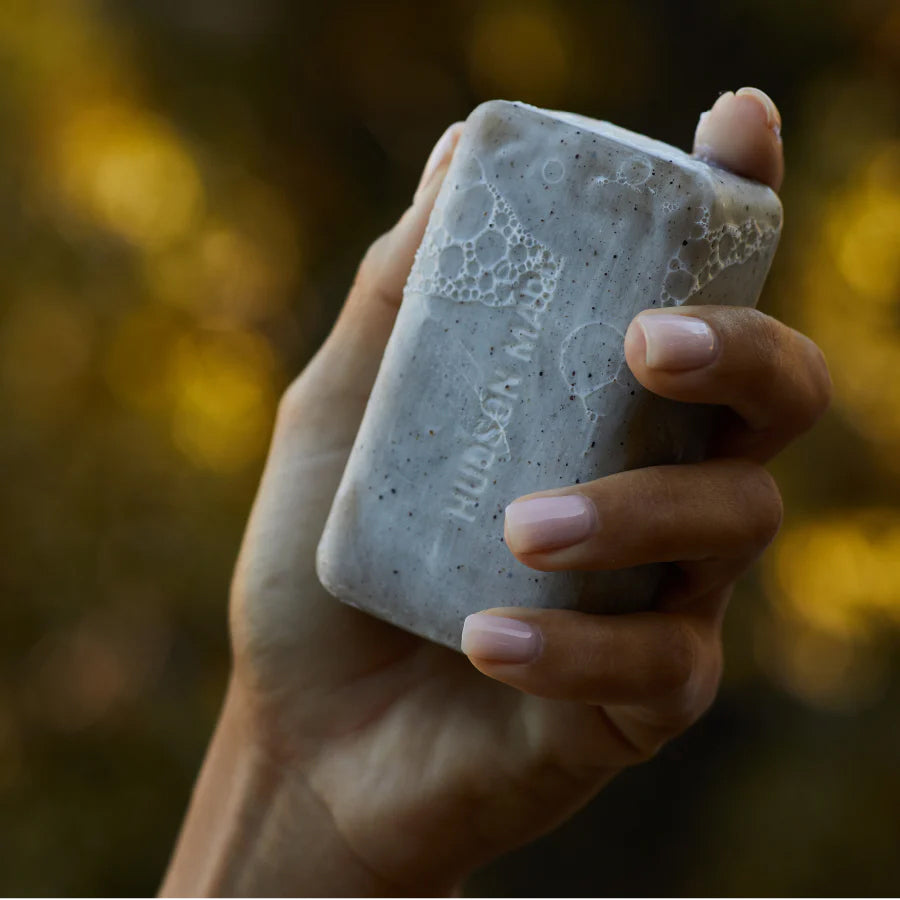 Close-up of hand holding a lathered Hudson Made embossed soap.  Slide 2 of 4