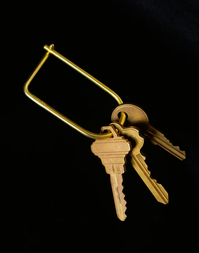 3 of 3 Set of keys attached to a brass keychain on a black background