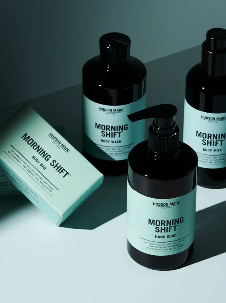 There are three amber bottles of Morning Shift (body wash, hand soap, body milk) with a boxed body bar soap.  The labels and box are in a teal color with black text.
slide 4 of 4