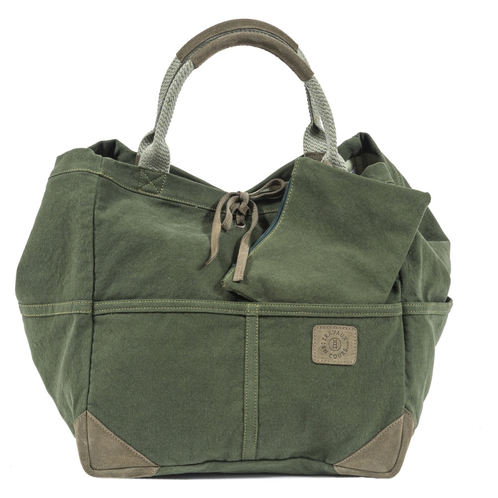 Front view of the green large tote bag with two curved handles with leather trim.  Khaki green leather tie in the center of bag with khaki green logo patch on center right of bag.  Rectangular zip pocket is pulled out from the interior to show independent functionality.  Slide 2 of 5