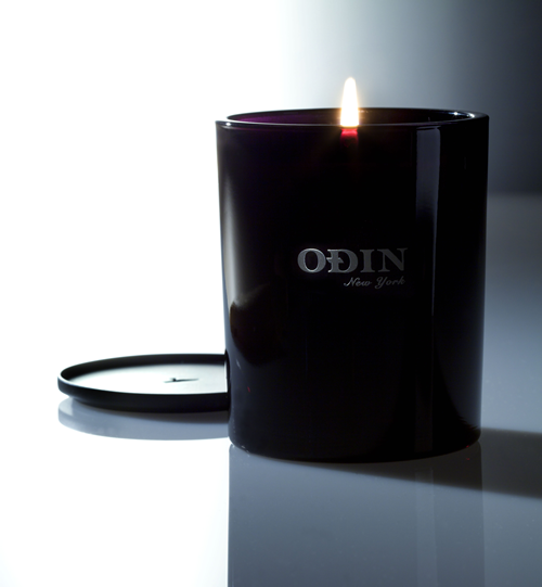 01 Sunda fullsize candle that is lit with Odin New York logo printed on outside of the black vessel.  The Black Metal cap is shown behind and next to the candle.