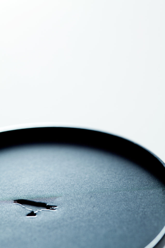 Close-up of the black votive lid with deboss raven logo on the center of the metal lid