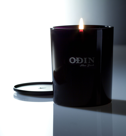 02 Owari fullsize candle that is lit with Odin New York logo printed on outside of the black vessel.  Metal cap is shown behind and next to the candle.