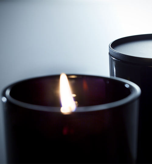 01 Sunda black votive size candle lit and a secondary candle with metal lid on top