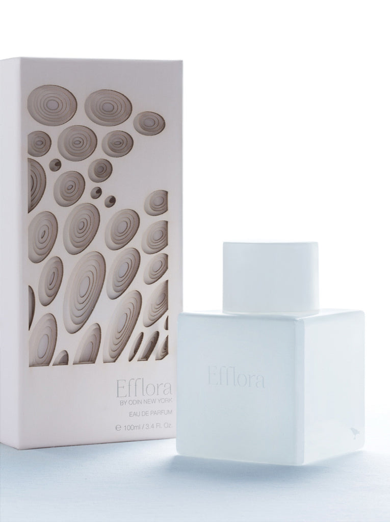 Efflora EDP in a white bottle with white cap.  Efflora is printed on the bottle.  Light pink Efflora box with circle like pattern cut to show depth.